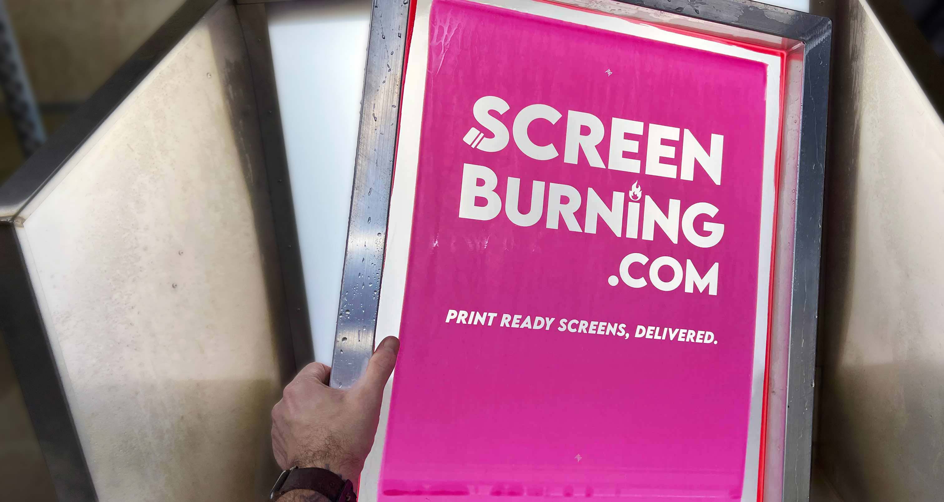 A hand holding a pre-burned screen with the ScreenBurning.com exposed into it
